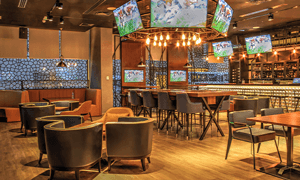 A contemporary sports bar featuring multiple screens, stylish furniture, and ambient lighting for a perfect entertainment experience.